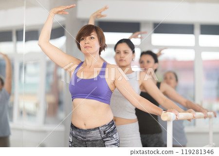 Group of women stand in fourth position at barre 119281346