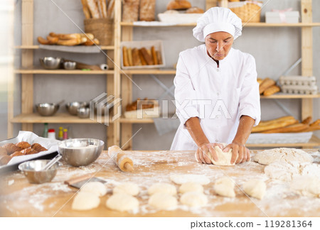 Mature woman baker kneading dough Mature woman baker kneading dough 119281364