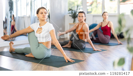 Young female yoga instructor performing Ardha Matsyendrasana with group of women 119281417