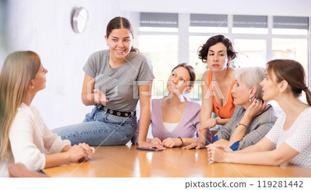 Smiling young girl discussing with female volunteer group Smiling young girl discussing with female volunteer group 119281442