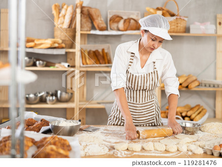 Adult woman rolls out dough with rolling pin Adult woman rolls out dough with rolling pin 119281476