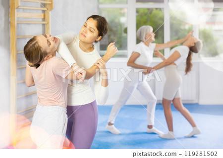 Girl paired up with woman to perform effective impact on pain points while learning self-defense. Girl paired up with woman to perform effective impact on pain points while learning self-defense. 119281502