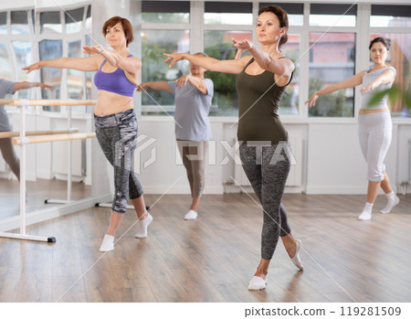 Woman leading ballet class with female amateur dancers in studio 119281509