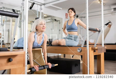 Aged woman exercising on wunda chair in pilates studio 119281540