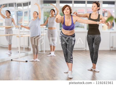 Female ballet trainer adjusting poses of middle aged woman in amateur class Female ballet trainer adjusting poses of middle aged woman in amateur class 119281561