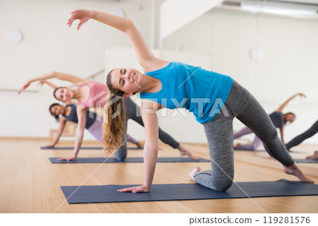 Girl standing in balancing pose Vasisthasana during yoga training Girl standing in balancing pose Vasisthasana during yoga training 119281576