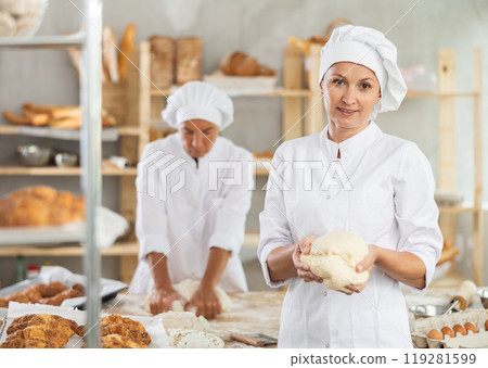 Two women bakers kneading dough in workshop Two women bakers kneading dough in workshop 119281599