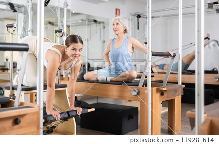Young girl practicing pilates stretching exercises on combo chair Young girl practicing pilates stretching exercises on combo chair 119281614