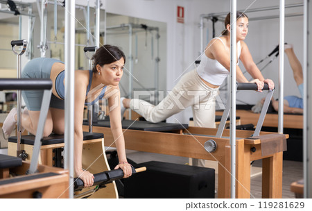 Young positive woman doing Pilates on special equipment in gym 119281629