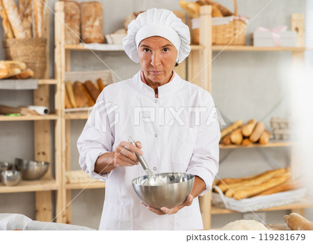Elderly woman baker whipping dough Elderly woman baker whipping dough 119281679