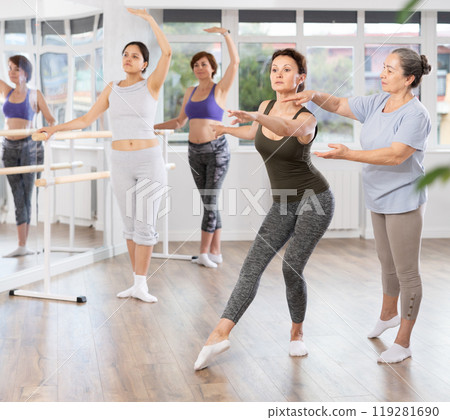 Elderly woman teacher correcting female dancers 119281690