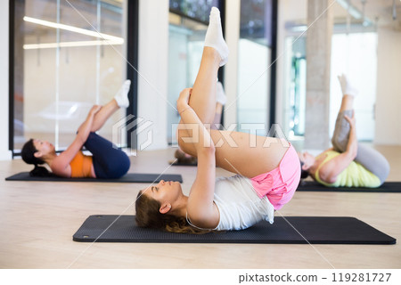 Group of women doing rolling back stretch Group of women doing rolling back stretch 119281727