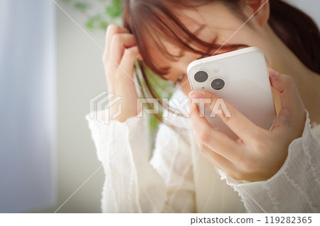 A woman with a dull expression looking at her smartphone 119282365