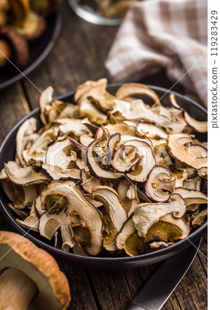 Dried porcini mushrooms. Sliced boletus on plate on wooden table. 119283429