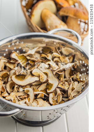 Dried porcini mushrooms. Sliced boletus in colander on white table. Dried porcini mushrooms. Sliced boletus in colander on white table. 119283438