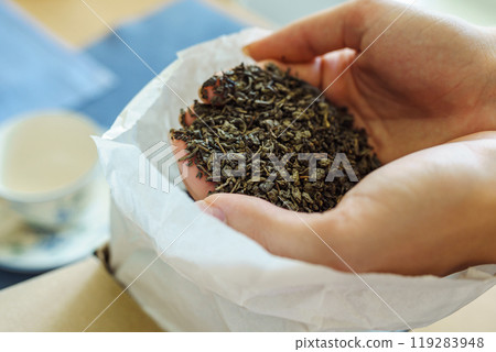 Woman holding paper bag with dry green tea leaves, close up 119283948