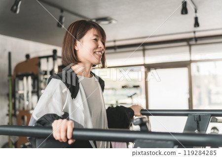 Asian woman walking and doing aerobic exercise on a treadmill/running machine in a sports gym 119284285