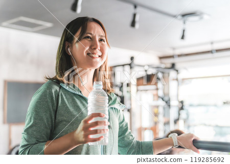 Asian woman walking and doing aerobic exercise on a treadmill/running machine in a sports gym 119285692
