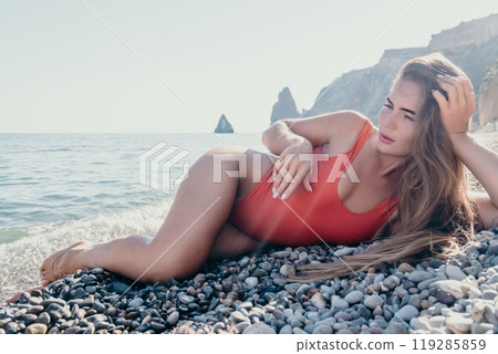 Woman in Red Swimsuit Relaxing on a Pebble Beach 119285859