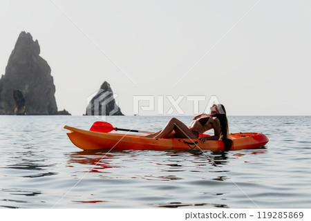 Kayaking Woman Sea Rocks Scenic View, Woman kayaking in ocean with scenic rock formations in the background. Kayaking Woman Sea Rocks Scenic View, Woman kayaking in ocean with scenic rock formations in the background. 119285869