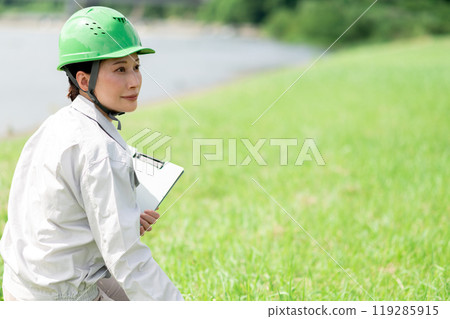 A woman in work clothes wearing a helmet surveying geology 119285915