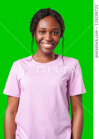 Young woman smiling joyfully in a pink shirt against a vibrant green background in a cheerful atmosphere Young woman smiling joyfully in a pink shirt against a vibrant green background in a cheerful atmosphere 119286722