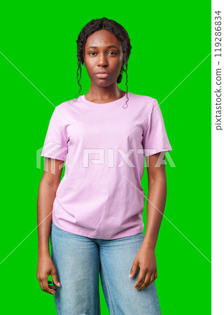Young woman with an expression of contemplation poses against a bright green background 119286834
