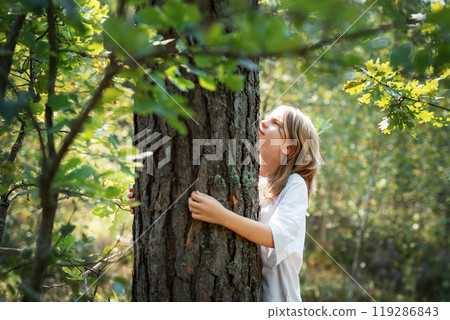 A teenage girl hugs a tree in the forest. A teenage girl hugs a tree in the forest. 119286843