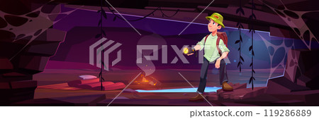 Male traveler standing in cave with flashlight 119286889