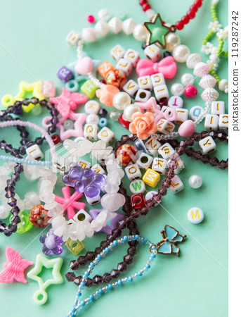 Colorful beads and charms scattered on a blue surface, showcasing various shapes and colors 119287242