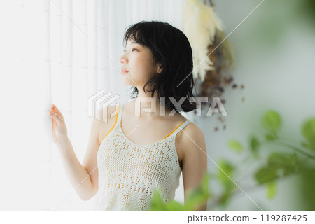 Woman opening curtain Woman opening curtain 119287425