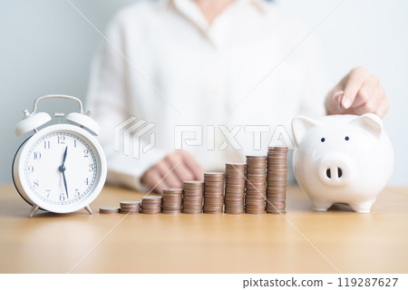 Money Saving for Future Plan, Retirement fund, Pension, Investment, Wealth Business and Financial concepts. hand putting coin into piggy bank with clock, Counting and stack arrangement for deposit 119287627