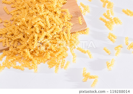 Uncooked Fusilli Pasta Scattered on Wooden Board 119288014