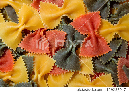 Dry Uncooked Colored Farfalle Pasta and Raw Macaroni on a Textured Background Dry Uncooked Colored Farfalle Pasta and Raw Macaroni on a Textured Background 119288047