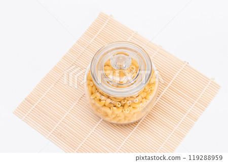 Uncooked Chifferi Rigati Pasta in Glass Jar on Bamboo Mat 119288959