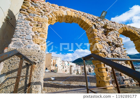 Wide angle view of Cefalu town through stone arch gate, Sicily, Italy 119289177