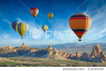 Colorful hot air balloons fly in blue sky over amazing valleys with fairy chimneys in Cappadocia, Turkey 119289309