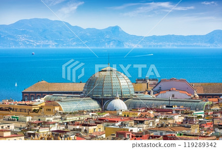 Domes of Galleria Umberto I towering over roofs of neighboring houses in Naples on background of Tyrrhenian Sea, Italy. Domes of Galleria Umberto I towering over roofs of neighboring houses in Naples on background of Tyrrhenian Sea, Italy. 119289342