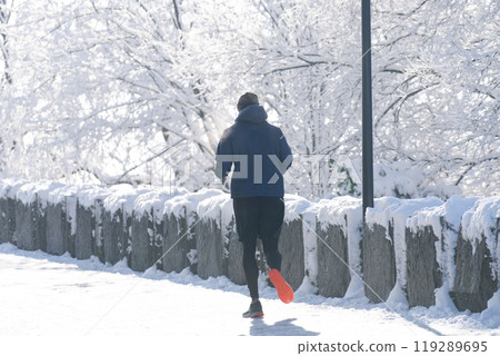 The man is jogging in the winter park 119289695