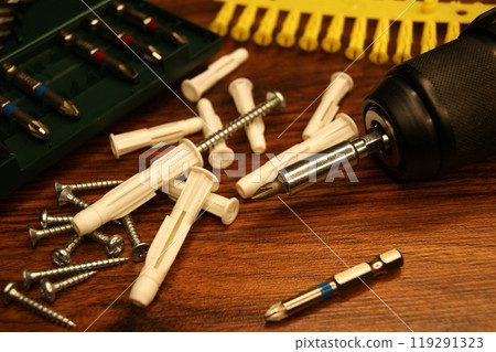 A mess in the assembly work process on the table. Dowels, screws, screwdriver, bit set. 119291323