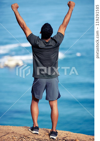 Man, exercise and mountain celebration at cliff with fist for hiking victory or outdoor view, back or workout. Male person, trekking and health goals at ocean or explore Australia, journey or winner 119291585