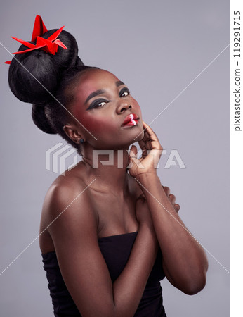 Woman, beauty portrait and origami in studio for creative makeup with red, Asian culture and paper bird. African model, bold cosmetic and grey background for art deco, confidence and Japanese design 119291715