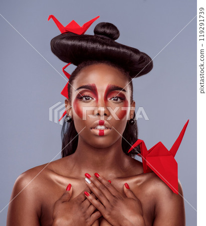 Portrait, makeup and black woman with origami for beauty in studio isolated on gray background. Face, creative cosmetics and confident young model with oriental paper crane in hair, skincare and art Portrait, makeup and black woman with origami for beauty in studio isolated on gray background. Face, creative cosmetics and confident young model with oriental paper crane in hair, skincare and art 119291739