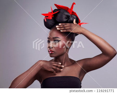 Woman, beauty and origami in studio for creative makeup with red, Asian culture and paper bird. African model, bold cosmetics and grey background for art deco with confidence and Japanese design 119291771