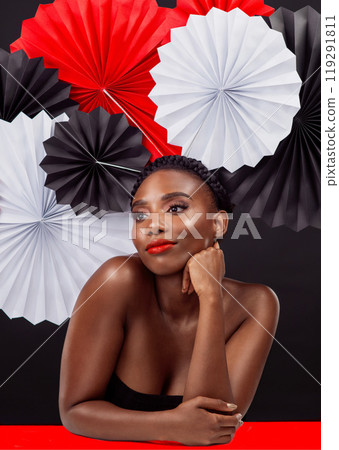 Creative, thinking and black woman with origami fans in studio, beauty and dark background. Face, makeup and cosmetics of female model with pride, traditional, smile and and paper art for culture hat Creative, thinking and black woman with origami fans in studio, beauty and dark background. Face, makeup and cosmetics of female model with pride, traditional, smile and and paper art for culture hat 119291811