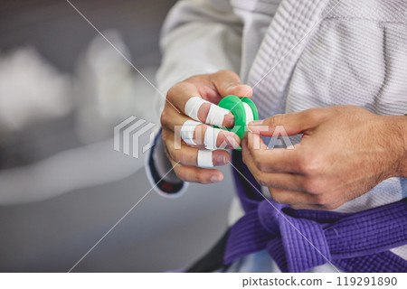 Brazilian jiu jitsu, hands and person with tape in gym for training, fitness or professional fighting sport. Injury, protection and martial arts athlete with gi, safety for fingers or workout in dojo Brazilian jiu jitsu, hands and person with tape in gym for training, fitness or professional fighting sport. Injury, protection and martial arts athlete with gi, safety for fingers or workout in dojo 119291890