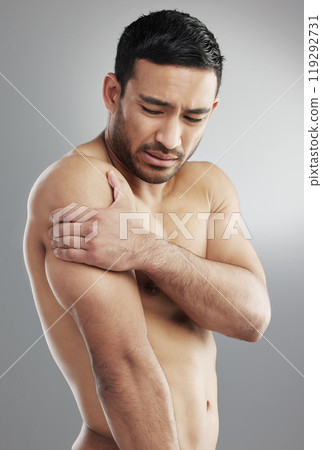 Studio, man and shoulder pain after fitness, muscle injury and tension as bursitis symptom. Face, arm and asian model with inflammation, sports or training accident by gray background with emotion 119292731