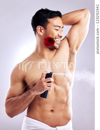 Man, grooming and smile with deodorant and rose in studio background for hygiene, cleanliness and wellness. Male person, happy and confident with spray for odor, fragrance and freshness or healthcare 119292941