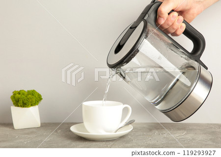 Kettle pouring boiling water into a cup on grey background. 119293927