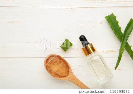 Aloe vera gel on wooden spoon with aloe vera and oil bottle on white background. Vertical photo 119293981